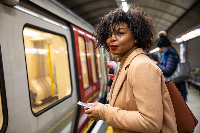 woman waiting for train holding phone