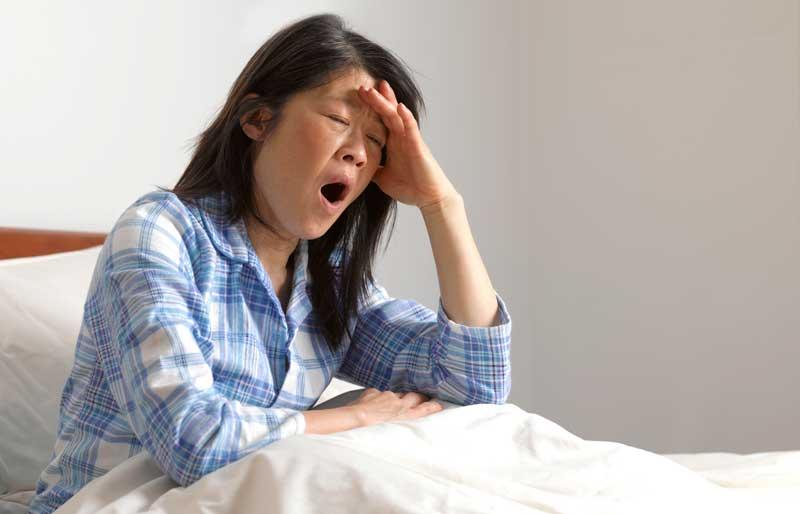 Sleepy woman yawning in her bed