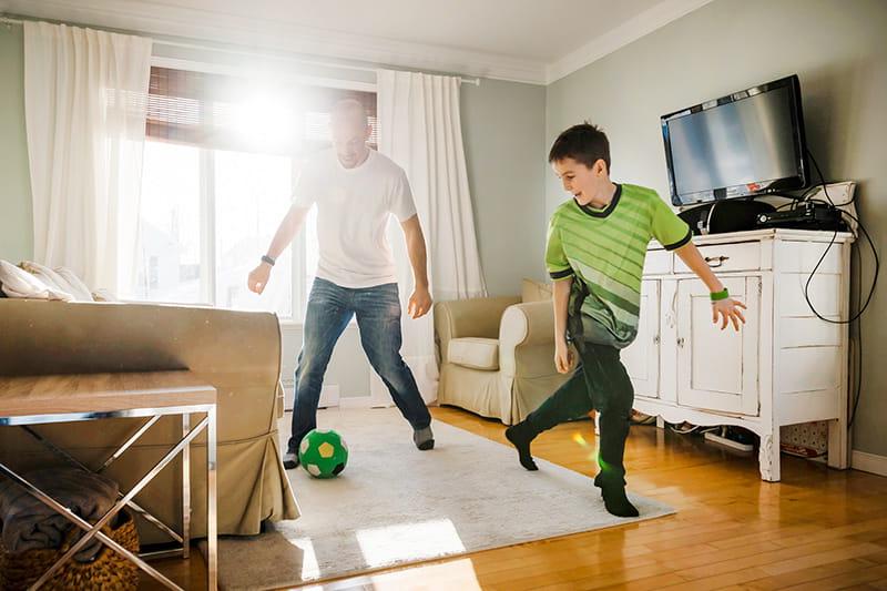 dad and son play indoor soccer at home