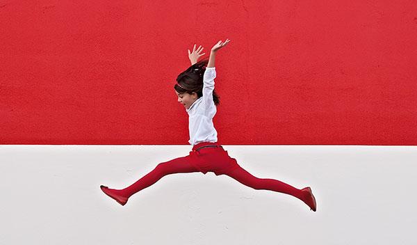 Girl jumping in front of red background